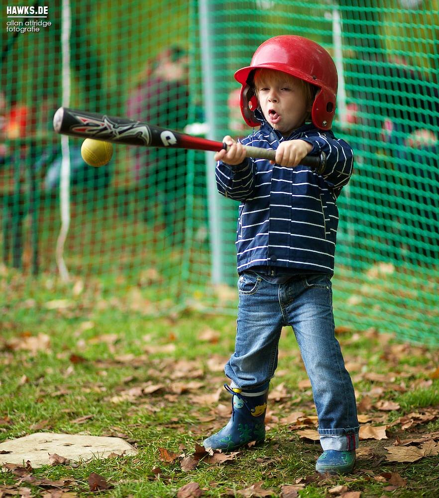 Kleinkind mit Helm schlägt den Ball